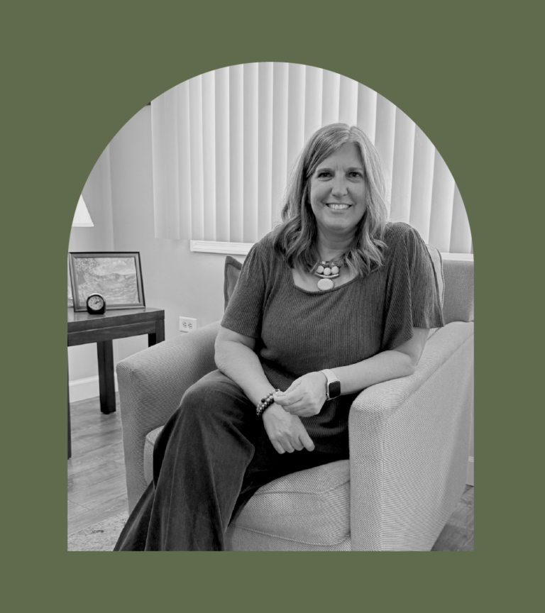 Laurie sits in a chair and smiles.